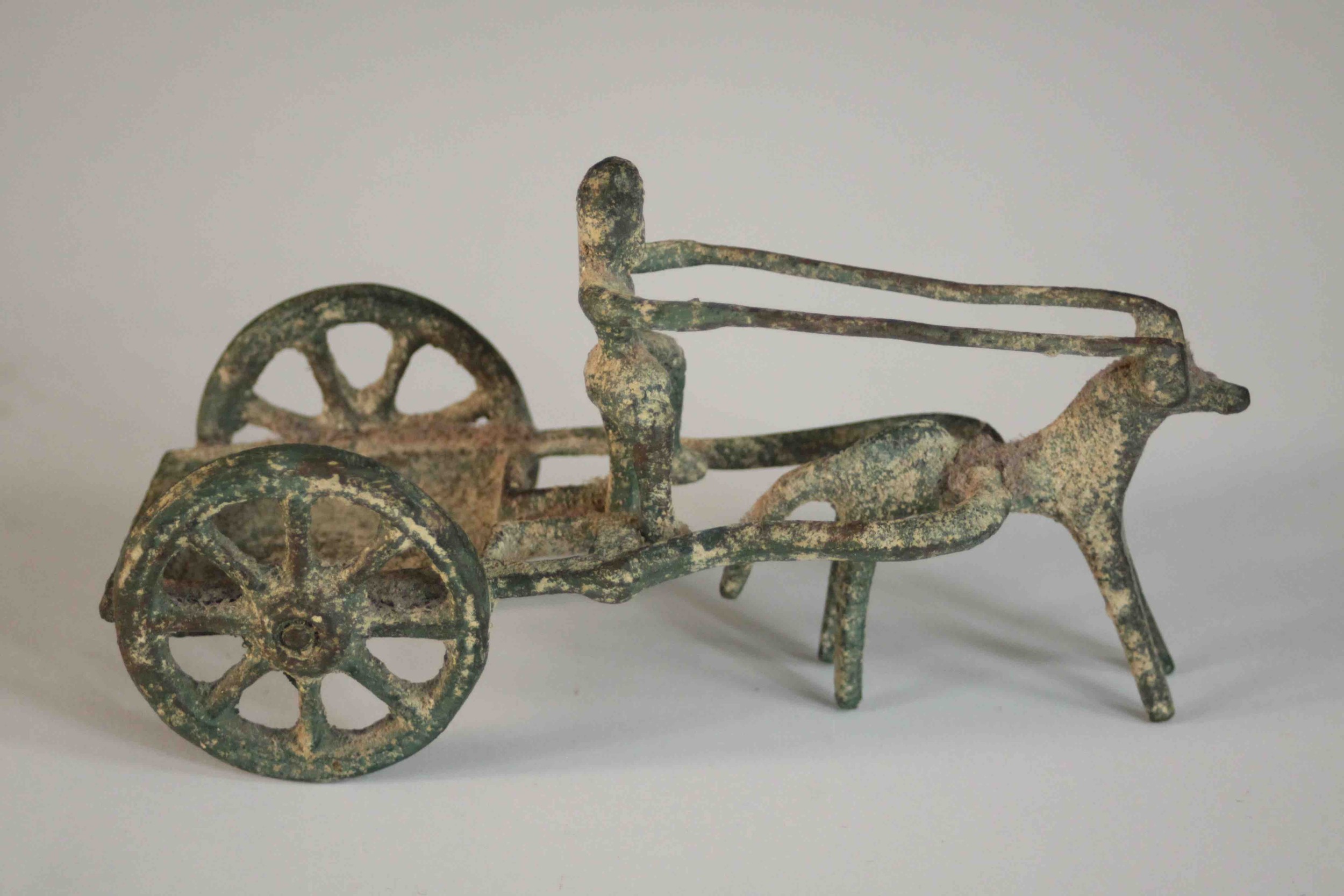 An ancient Greek style bronze of a man riding a horse drawn cart. H.8 W.14 D.6cm.