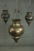 Three Middle Eastern brass mosque lamps, each hung on three chains with a bulbous pierced body and a