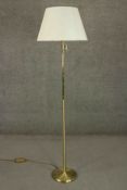 A contemporary brass reading lamp, with an adjustable arm and a pink shade, on a circular base. H.