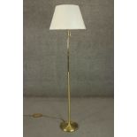 A contemporary brass reading lamp, with an adjustable arm and a pink shade, on a circular base. H.