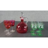 Three Victorian cranberry glass cordial glasses and decanter with twisted handle along with a set of