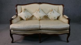 A late 20th century French show wood two seater sofa, with a carved frame, upholstered in cream