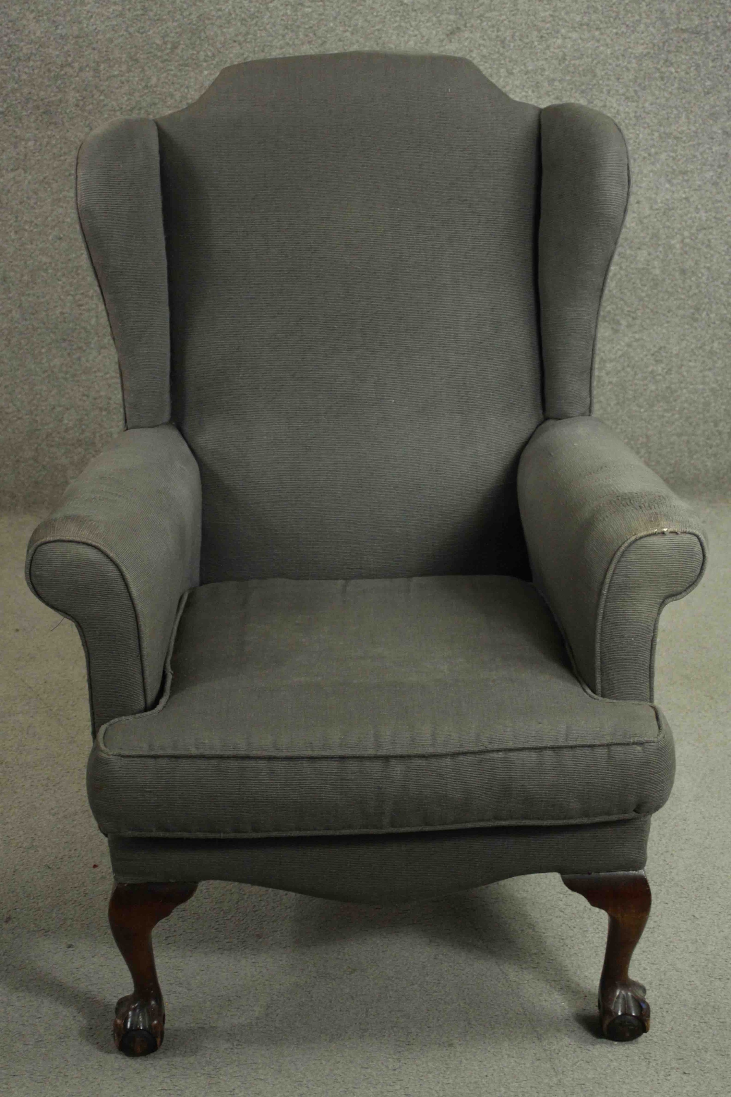 A Victorian wing back armchair, upholstered in grey fabric with scroll arms, on mahogany cabriole
