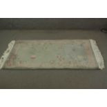 A Chinese rug with bird and flower motif on a jade ground. L.160 W.93cm.