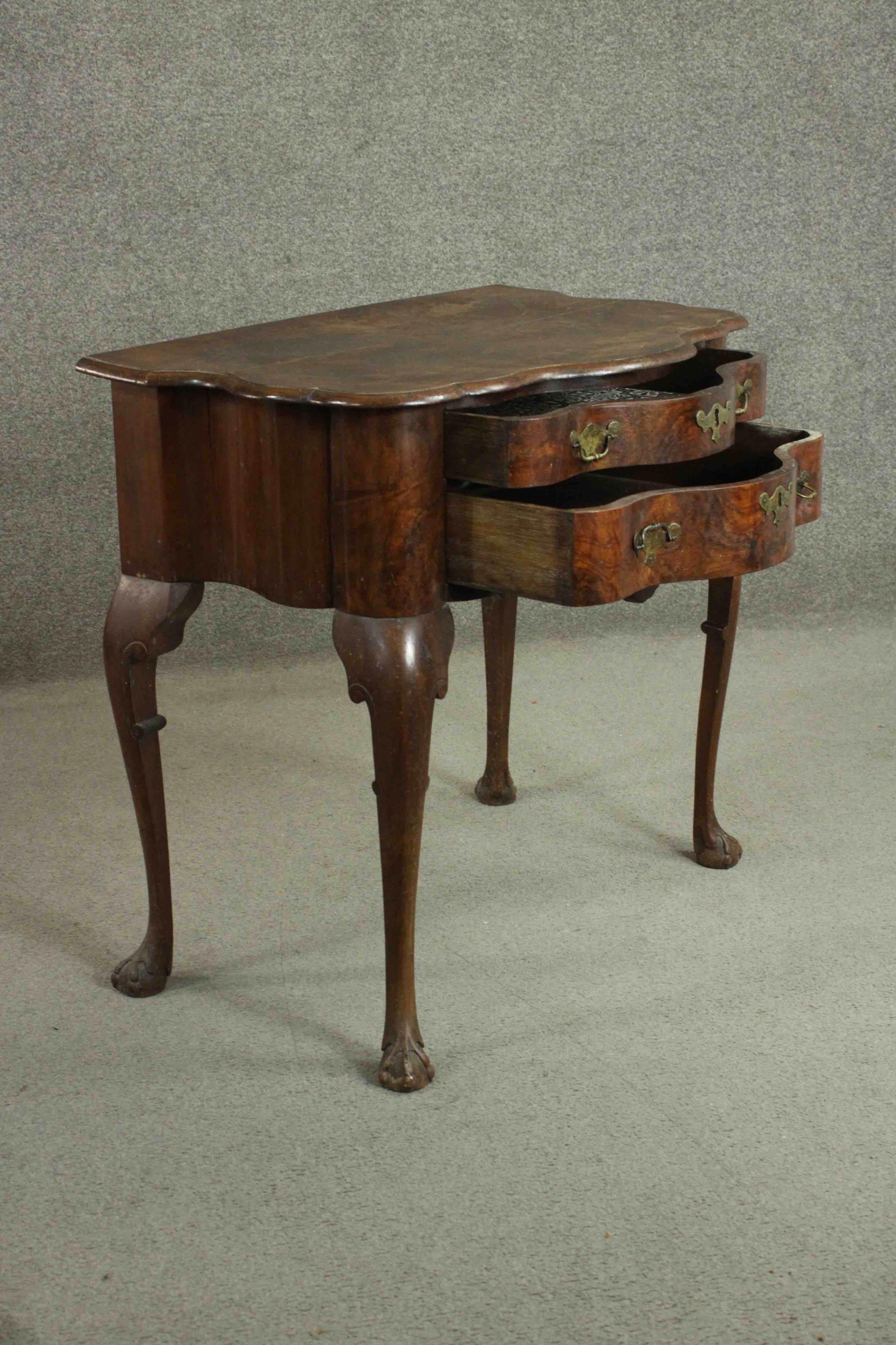 An early 18th century figured walnut lowboy of serpentine form, the top with a moulded edge over two - Image 4 of 8