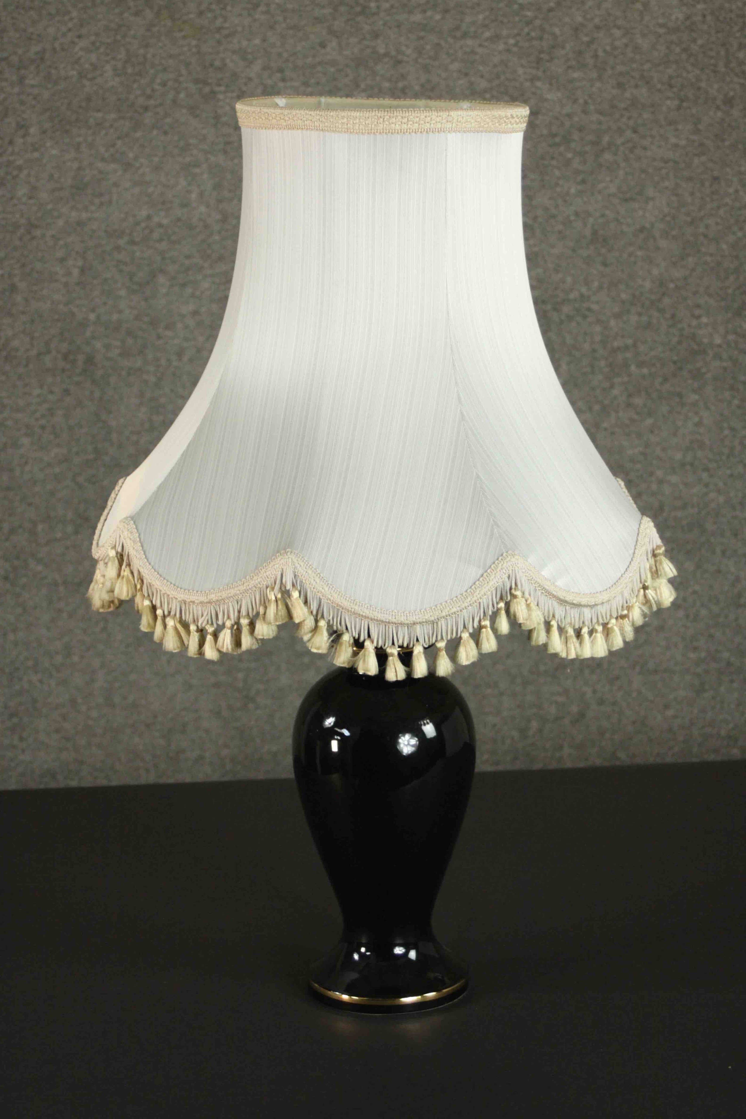 A late 20th century black glazed ceramic baluster form table lamp, with a cream coloured shade. H.75