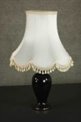 A late 20th century black glazed ceramic baluster form table lamp, with a cream coloured shade. H.75