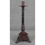 A Vitetnamese floor standing candlestick, painted in hues of red and black, the reeded stem with