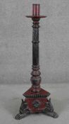 A Vitetnamese floor standing candlestick, painted in hues of red and black, the reeded stem with