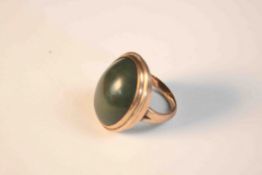 A pink metal (tests as 9ct gold) and green stone cabochon dress ring, set with an oval green