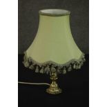 A brass table lamp, hung with faceted glass lustres on a cast feather base, with a pale green shade.