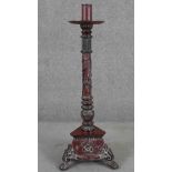 A Vietnamese floor standing candlestick, painted in hues of red and black, the reeded stem with