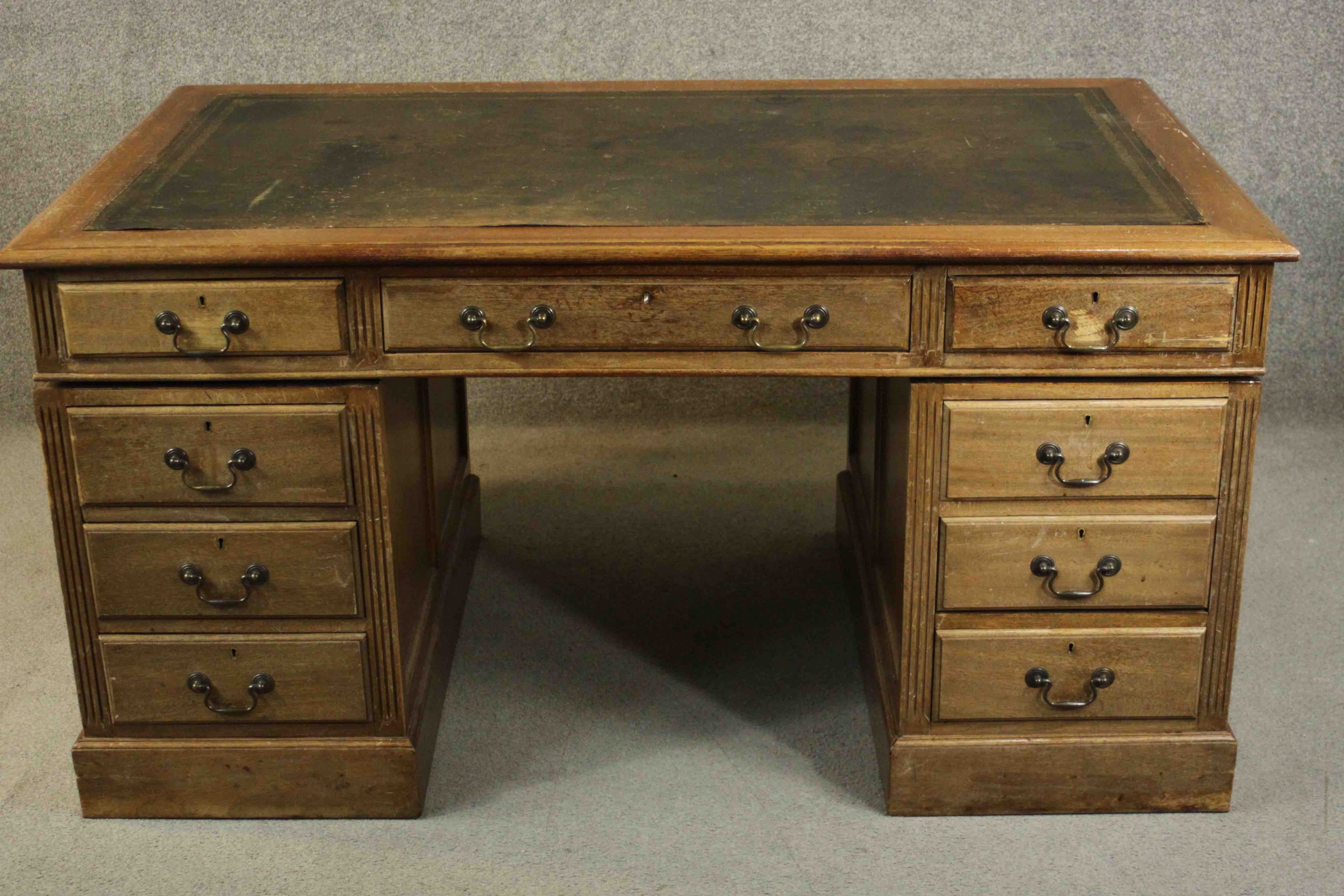 An early 20th century pedestal desk, with a leather writing insert over an arrangement of nine