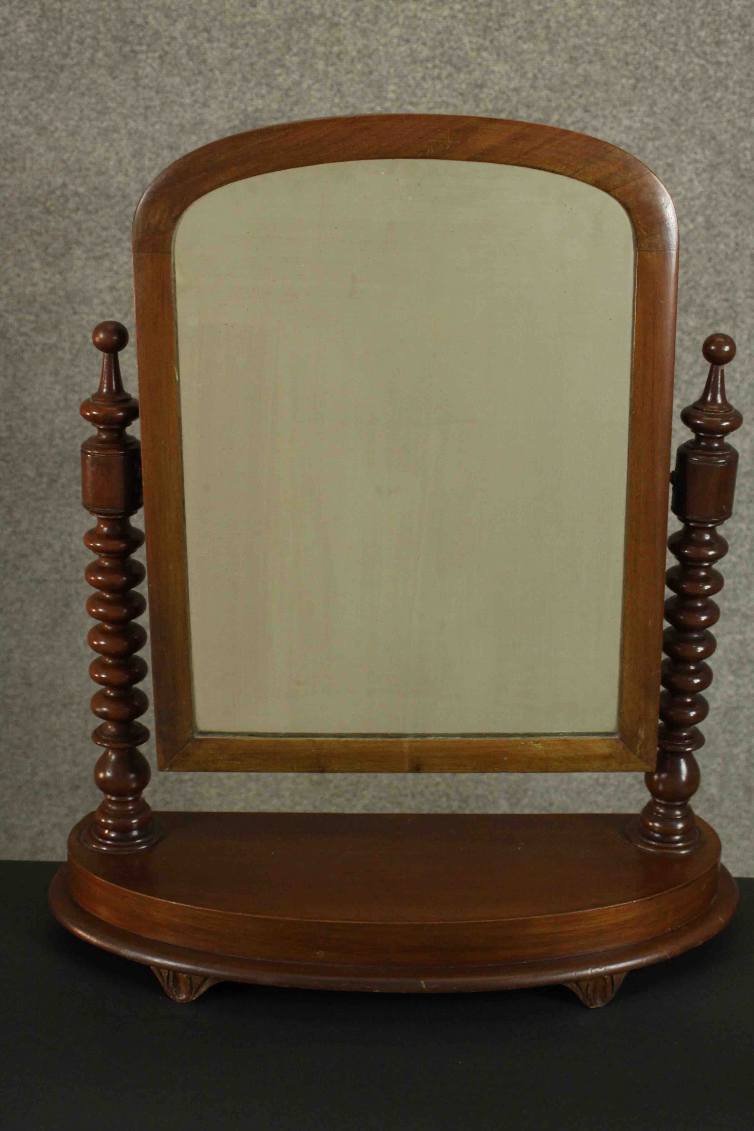 A Victorian walnut dressing table or toilet mirror, of rounded arch form supported by bobbin