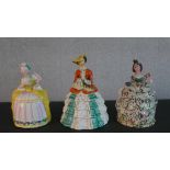 Three hand painted ceramic lidded biscuit jars in the form of Victorian ladies with crinolinned