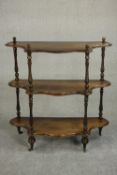 An early 20th century Continental walnut whatnot, of serpentine form with three shelves, turned