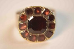 A Georgian yellow metal and foil backed garnet cluster ring. Set to the centre with a cushion shaped