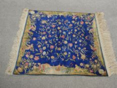 A silk Chinese rug with flowerhead design across the sapphire ground with Classical figural