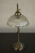 An early 20th century style brass desk lamp, with a holophane style glass shade, adjustable stem and