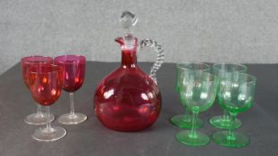 Three Victorian cranberry glass cordial glasses and decanter with twisted handle along with a set of