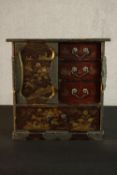 A Japanese Meiji period lacquered tabletop cabinet, painted with gilded flowers and landscapes, with