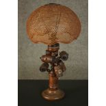 A treen turned pine table lamp, adorned with turned barrels, under a dome form caned shade. H.53 W.