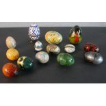 A collection of fourteen eggs, including a ceramic box, hand painted wooden eggs, a Russian