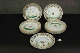 A set of eleven 19th century hand painted porcelain plates with pierced gilded lattice work rims and