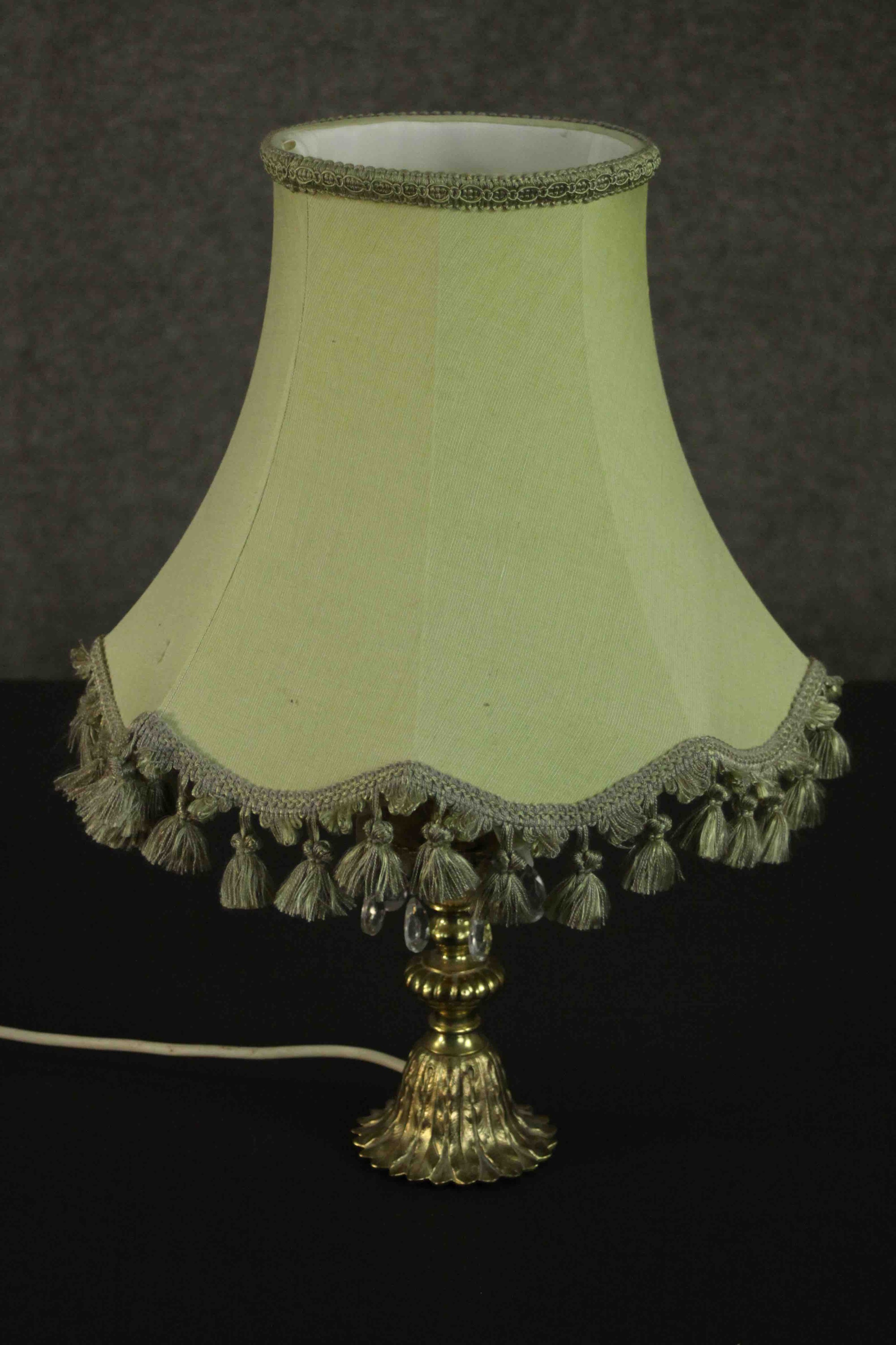 A brass table lamp, hung with faceted glass lustres on a cast feather base, with a pale green shade.