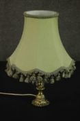 A brass table lamp, hung with faceted glass lustres on a cast feather base, with a pale green shade.