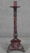 A Vietnamese floor standing candlestick, painted in hues of red and black, the reeded stem with