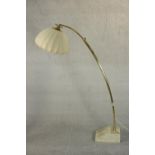 A 1970s brass arc floor lamp, of tubular extending form with a lobed fabric shade, on a marble base.