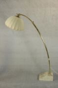 A 1970s brass arc floor lamp, of tubular extending form with a lobed fabric shade, on a marble base.