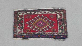 A hand woven Persian Hamadan rug, the hooked central medallion on a burgundy ground. L.60 W.36cm.