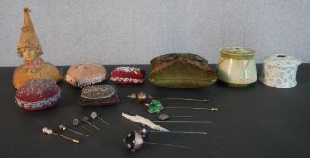 A collection of vintage pin cushions, hat pin holders and hat pins. Pin cushions include a beaded