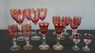 A collection of etched and gilded stemmed cranberry and ruby drinking glasses, including two sets of