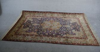 A hand woven Chinese silk rug with central floral medallion within flowerhead spandrels and
