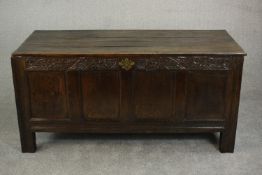 A 17th/18th century oak coffer, of panelled construction with a plank top, the four panels to the