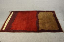 A Persian Gabbeh rug, burgundy and beige patterns on a mauve ground. L.175 W.130cm.