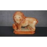 A Victorian Staffordshire figure of a male lion, one foot on a ball, raised on a rectangular base