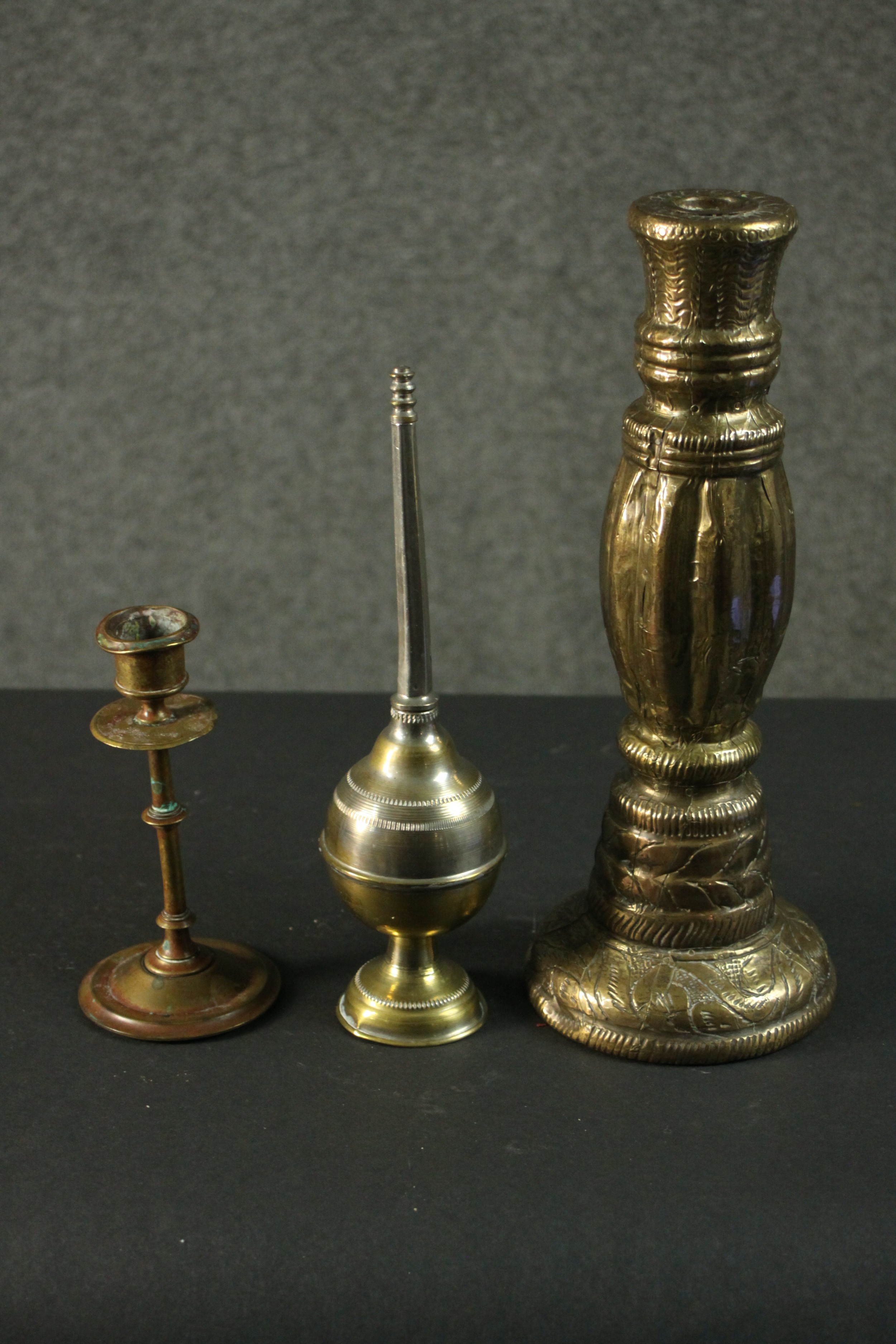 Three Indian brass items, comprising an ornately decorated candlestick, another candlestick, and a