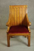 An early 20th century gothic revival oak armchair, the square back with rounded arch decoration over