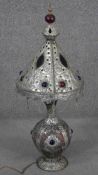 An Indian or Middle Eastern metalware lamp and shade, with embossed designs, glass panels and