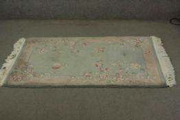 A Chinese rug with bird and flower motif on a jade ground. L.160 W.93cm.