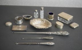 A collection of assorted silver items, including three boot hooks, a repousse design silver dish,