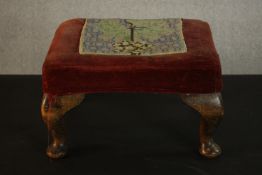 A footstool, upholstered in red velvet with an embroidered panel, on cabriole legs. H.22 W.36 D.