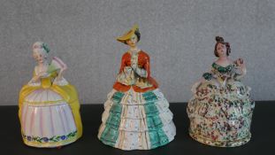 Three hand painted ceramic lidded biscuit jars in the form of Victorian ladies with crinolinned