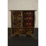 A Japanese Meiji period lacquered tabletop cabinet, painted with gilded flowers and landscapes, with