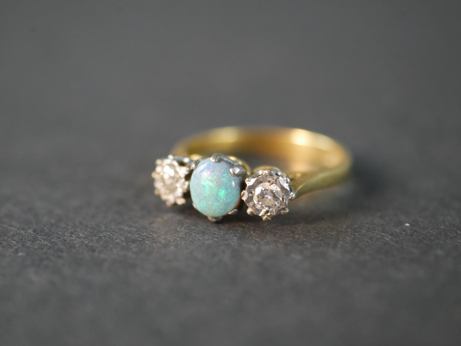 An 18 carat yellow gold and platinum Edwardian opal and diamond three stone ring, set to centre with