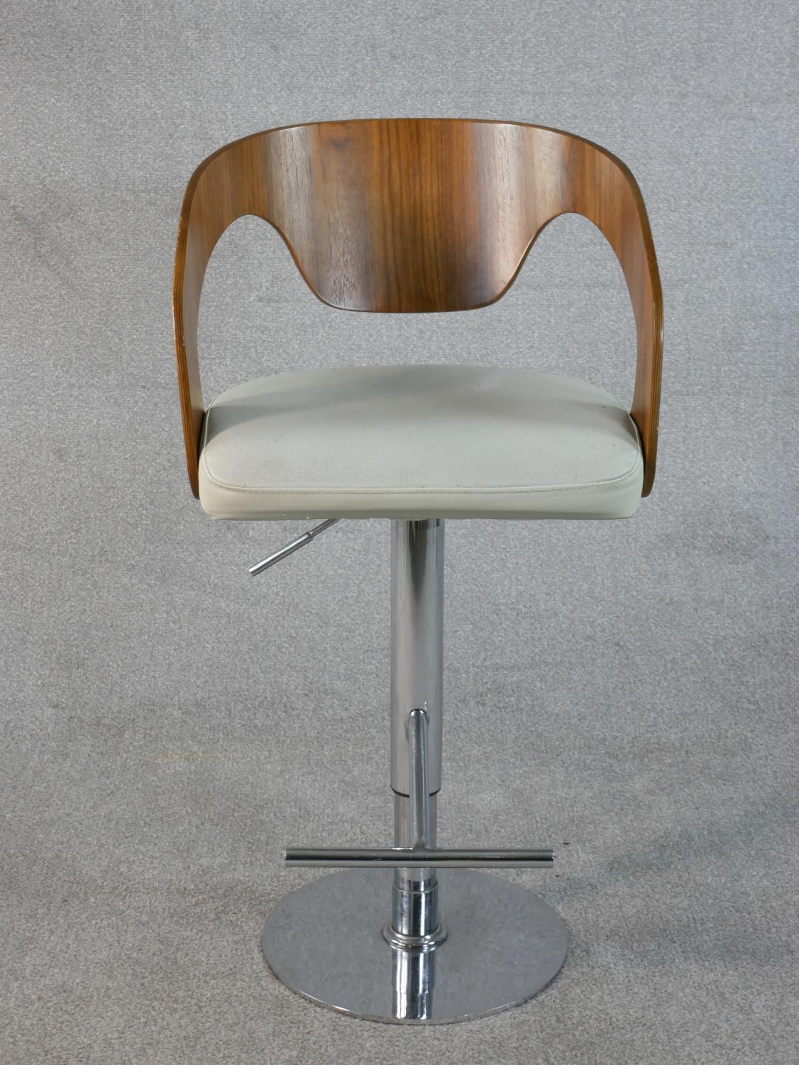 A contemporary adjustable height bar stool, with a curved walnut back and a white leather seat on